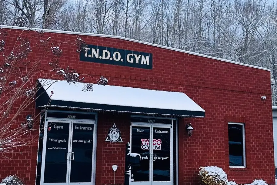 The red-brick TNDO GYM building and its entrance doors on a snowy morning