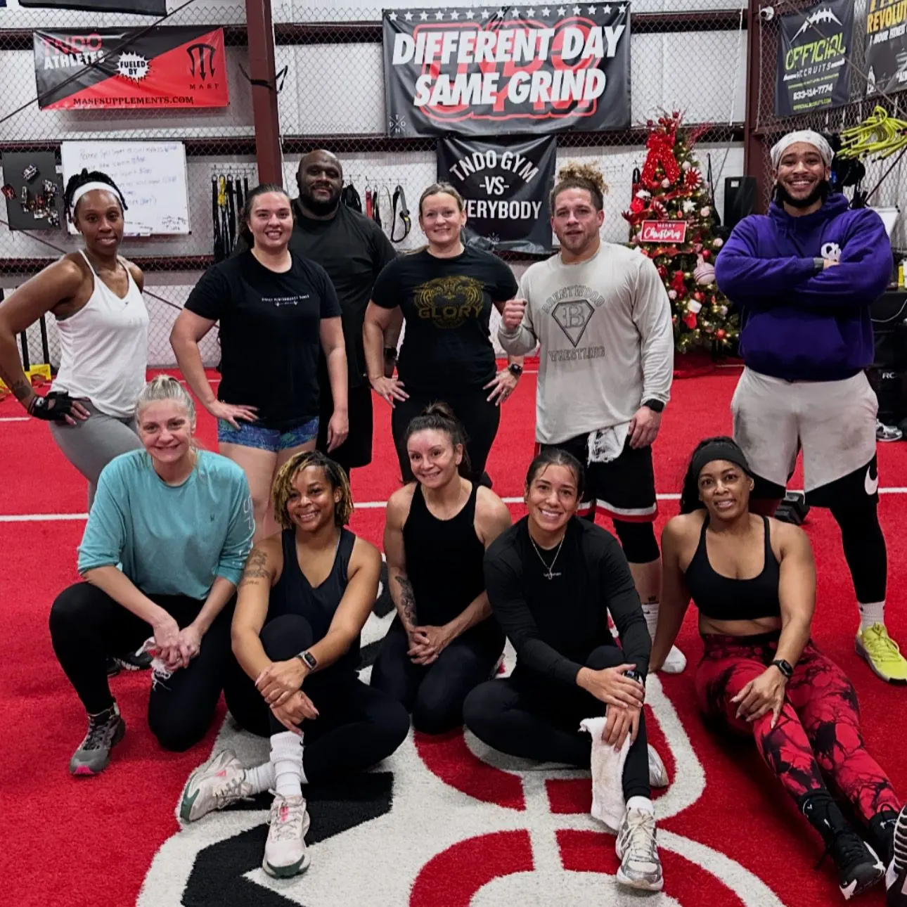 A smiling group of TNDO class members on the red turf after a workout