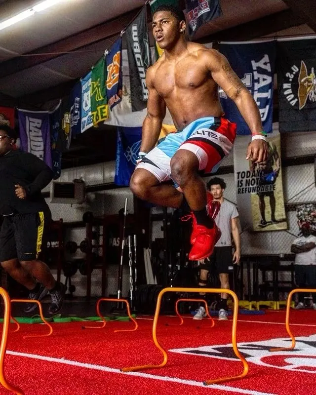 An athlete hops over mini hurdles on TNDO's red turf